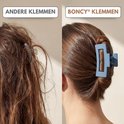 Vergelijking van een blauwe Boncy haarklem die een vrouw's haar netjes houdt, naast verward haar met een andere klem.