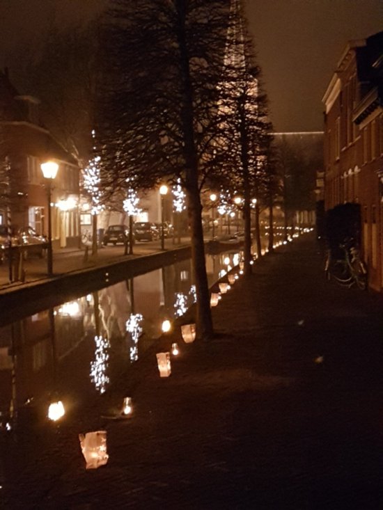 Straat langs een kanaal 's nachts, verlicht door papieren lantaarns.