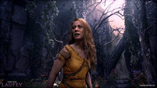 Vrouw met lang blond haar in een okergele jurk in een mysterieus, dichtbegroeid bos.