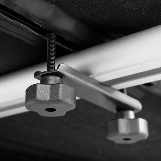 Bevestigingsmechanisme met twee draaiknoppen aan een rail onder een zwarte tas.