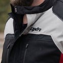 Detail van de kraag van een zwarte, lichtgrijze en rode motorjas met "DXR" logo.
