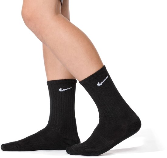Pieds d'une personne portant des chaussettes Nike noires, avec logos blancs sur les mollets.