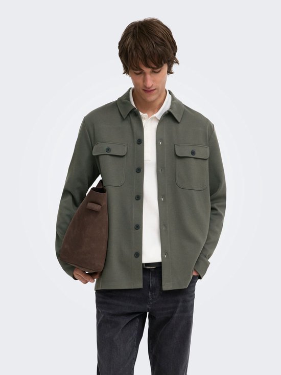 Man met donkerbruine tas, draagt een olijfgroene utility blouse over een wit poloshirt.