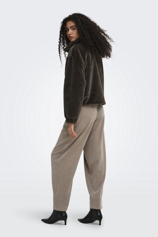 Model met krullend haar draagt een donkerbruine teddy jas met ritssluiting en een beige corduroy broek, achteraanzicht.