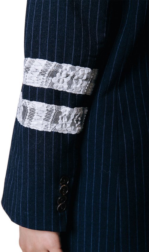 Detail van de witte kanten banden op de mouw van een donkerblauw pinstripe colbert.
