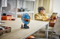 Man bouwt aan een LEGO McLaren F1 helm, blauw en oranje, met Lego-figuurtje.
