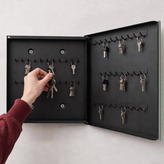 Hand die sleutels aan haken in een geopende zwarte sleutelkast hangt.