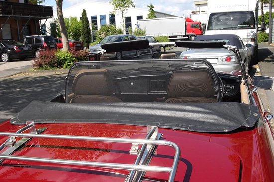 Zwart gaaswindscherm geplaatst achter de beige hoofdsteunen van een rode cabriolet.