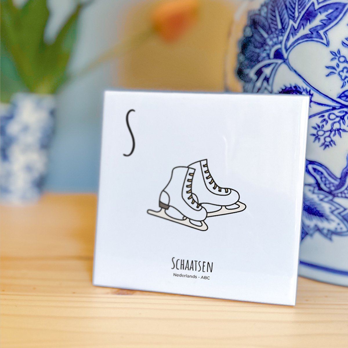 Schaatsen - ABC tegeltje Nederland - Keramiek met Handgetekende Illustratie - Wanddecoratie - Woondecoratie - Relatiegeschenk - Souvenir - 10,8 x 10,8 cm