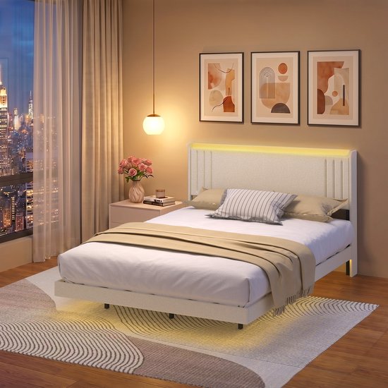 Lit capitonné de 160 x 200 cm avec tête de lit beige, entouré d'un éclairage LED d'ambiance, avec un plaid de couleur camel.