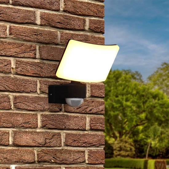Gedetailleerde weergave van de zwarte, rechthoekige wandlamp met bewegingssensor, gemonteerd op een bakstenen muur.