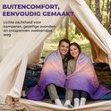 Een man en vrouw met een paars, roze en oranje gradiënt dekbed, zittend in een tent.