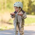 Lichtgroene kinderhelm met krokodillenprint, gedragen door een kind op een step.