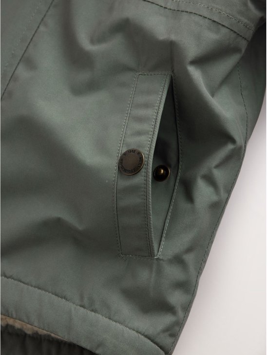 Detailopname van een zak van de groene parka met een metalen knoopsluiting.