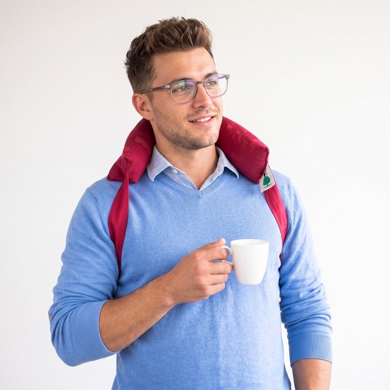 Man met bril met een rode warmtekussennekband, houdt een witte mok vast.