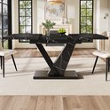 Eettafel in een moderne woonkamer, met zwart marmerlook blad en V-vormig onderstel.