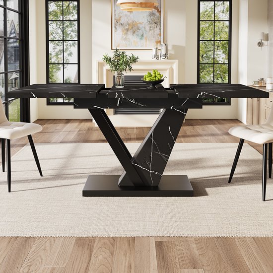 Eettafel in een moderne woonkamer, met zwart marmerlook blad en V-vormig onderstel.