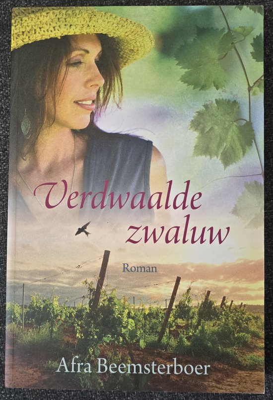 Boekomslag van 'Verdwaalde zwaluw' met een vrouw in een strooien hoed in een wijngaard.