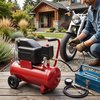 Rode luchtcompressor met zwarte motor, man vult motorband met motorfiets; gereedschapskist, drukmeter en slang liggen naast de compressor.