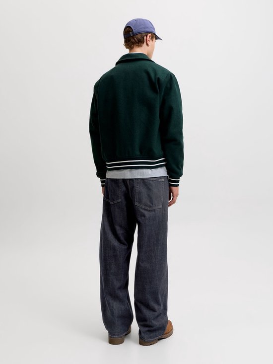 Achterkant van een model in een donkergroen jack en een wijde, donkere jeans.
