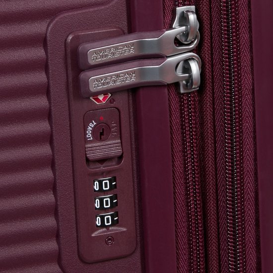 Sluitmechanisme van een bordeauxrode koffer met twee American Tourister handvatten, TSA-slot en cijferslot.