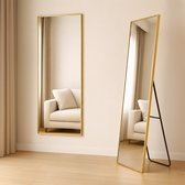 Twee hoge spiegels met gouden frame in een lichte kamer. Eén hangt aan de muur, de andere staat op een zwarte standaard.