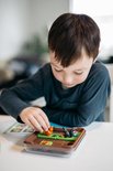 Jongen met donkere kleding speelt met eekhoorns en nootjes in een spel.