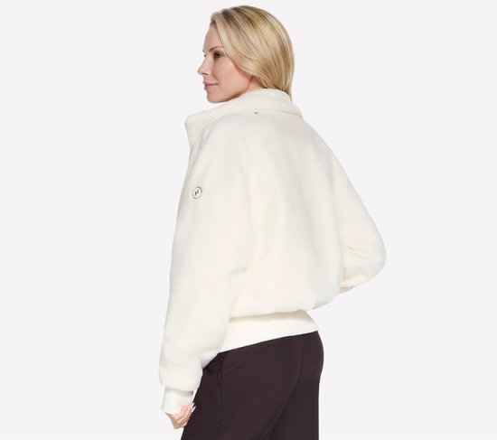 Model van opzij, off-white, cropped teddy jas met lange mouwen en een detail op de mouw.