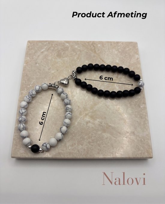 Twee armbanden van 6 cm, één met witte kralen met grijze lijnen en één met zwarte kralen. Beide met hartmagneet.