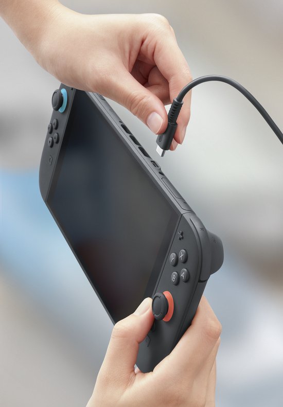 Hand die een grijze Nintendo Switch console oplaadt met een zwarte kabel.