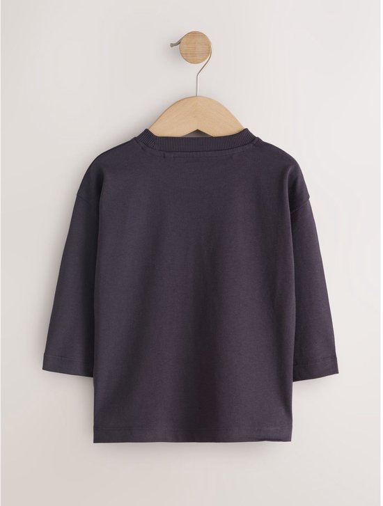Donkergrijs T-shirt met lange mouwen op een houten kleerhanger.