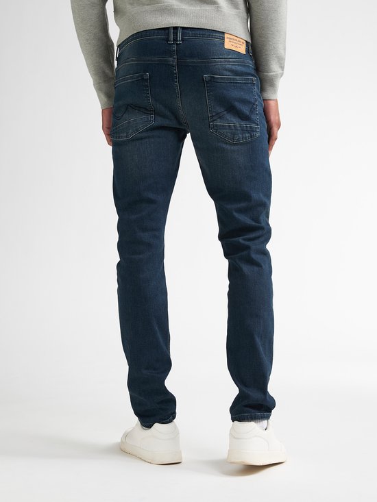 Achteraanzicht van een man in donkerblauwe jeans met lichte wassing, details op de achterzakken.
