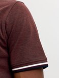 Detail van de mouw van een bordeauxrode polo met witte en marineblauwe streep aan de boord.