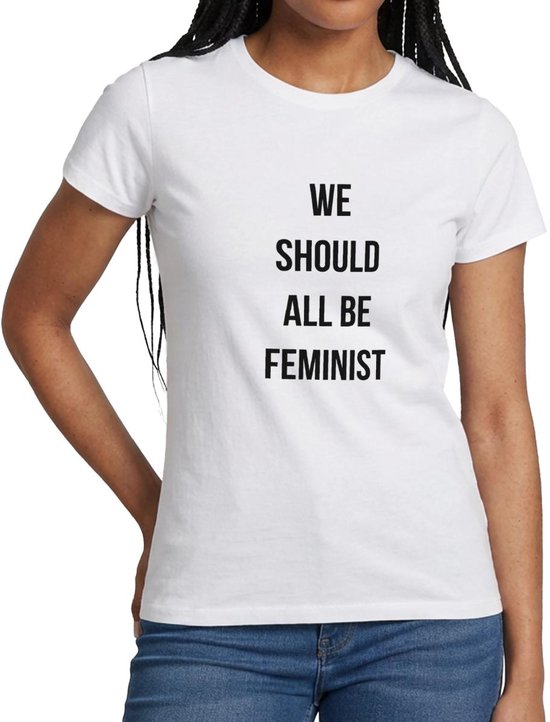Een vrouw met een wit T-shirt met de tekst "WE SHOULD ALL BE FEMINIST" in zwarte letters.