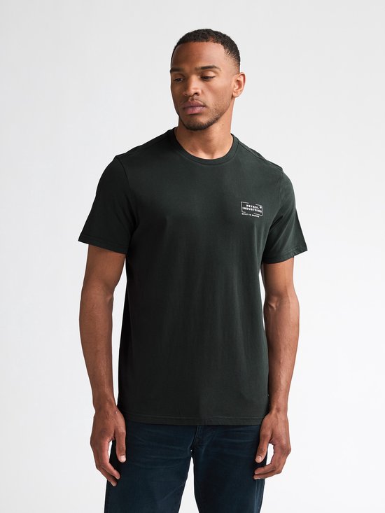 Man in donkergroen T-shirt met Petrol Industries logo op linkerborst. Draagt jeans.