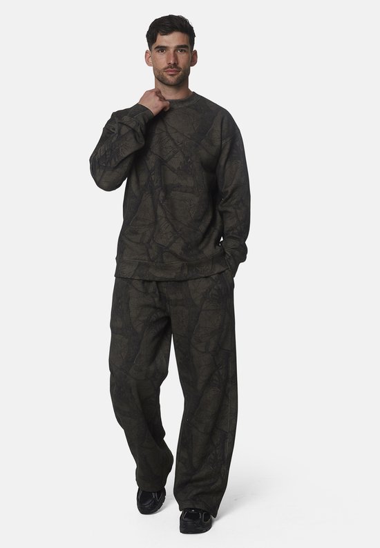 Man in donkergroen trainingspak met gebarsten patroon. Joggingbroek en sweater met lange mouwen.