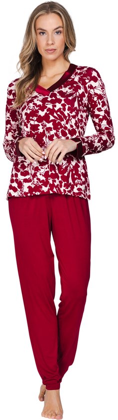 Model staat in een pyjama met bordeauxrode bloemenprint en effen rode broek.