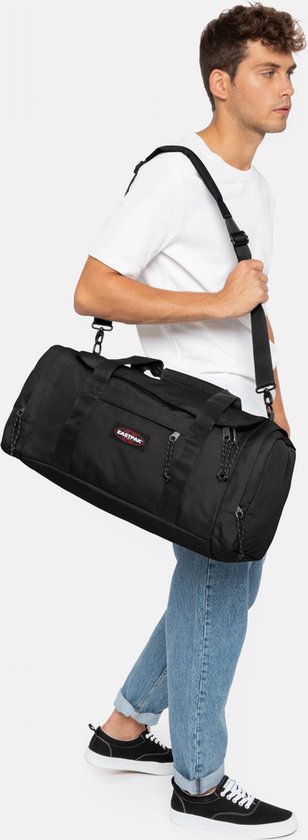 Man draagt een zwarte Eastpak Reader S+ reistas over zijn schouder.