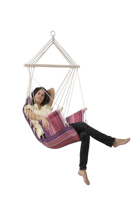 Vrouw in gele top en zwarte broek, zittend in gestreepte hangstoel (paars, roze).