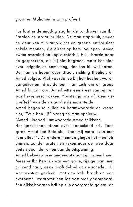 Man met grijze baard en hoed, gekleed in broek en overhemd, met bril.