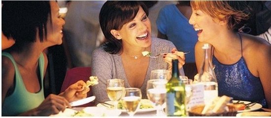 Drie vrouwen lachen aan een gedekte tafel