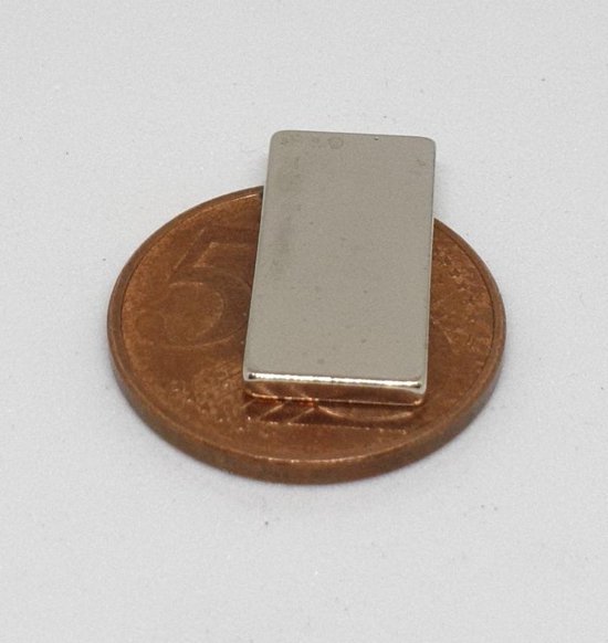 Eén zilverkleurig rechthoekig magneetje ligt op een 5-centmunt.
