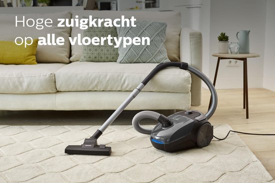 Philips stofzuiger op een kleed bij een bank. Tekst: 'Hoge zuigkracht op alle vloertypen'.