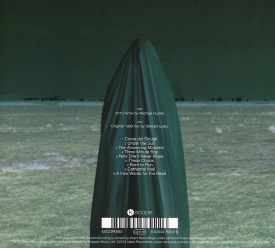 Een figuur in een donkergroene, met stof bedekte outfit, staande in een veld. Tekst voor "kscope" en tracklist zichtbaar.