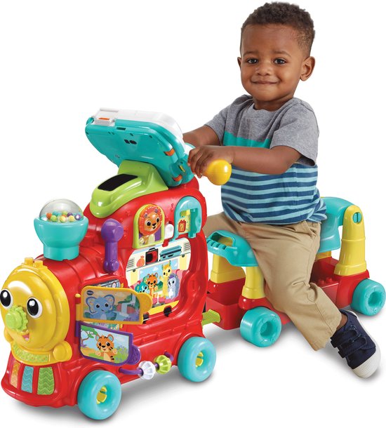 Een jongetje zit op een rode VTech trein met interactief paneel.