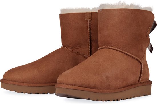 Bruine UGG laarsjes met witte schapenvacht voering, bruine strikjes op de achterkant en een dikke zool.