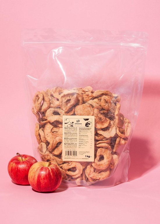 Grote plastic zak met gedroogde appelringen, twee rode appels ernaast.