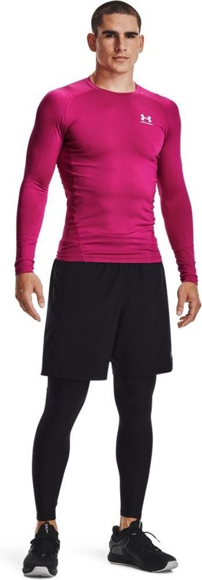 Man met lange roze shirt en zwarte shorts met daaronder een zwarte legging. Zwarte schoenen.