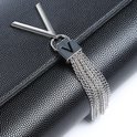Detail van het zilverkleurige V-logo met franjes op een zwarte clutch.