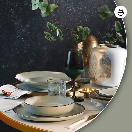 Gedekte tafel met beige aardewerken serviesgoed, gouden accenten en groene wijnglas.